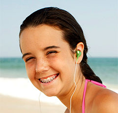 A girl wearing earphones on the beach.