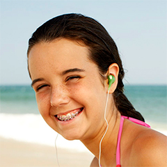 A girl wearing earphones on the beach.
