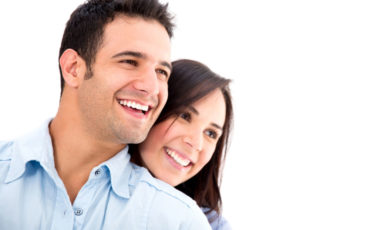 A man and a woman smiling against a white background.