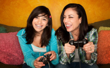 Two women playing video games on a couch.