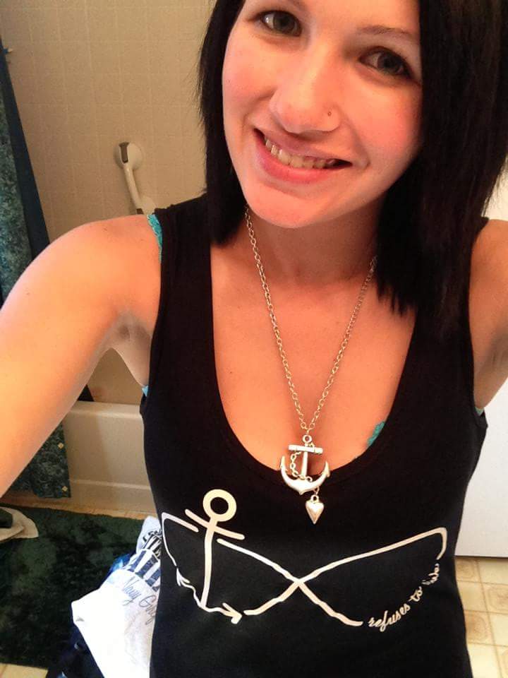 A woman in a black tank top is smiling at the camera.