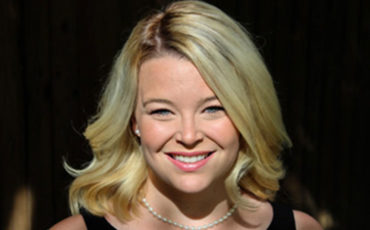 A woman in a black dress smiles for the camera.