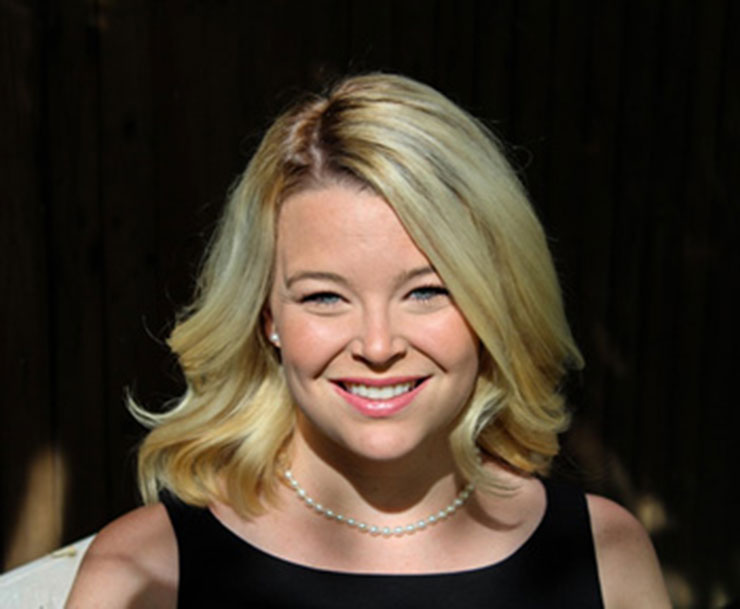 A woman in a black dress smiles for the camera.