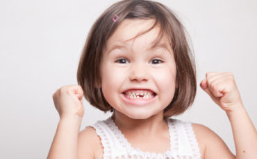 A little girl with her fists up in the air.