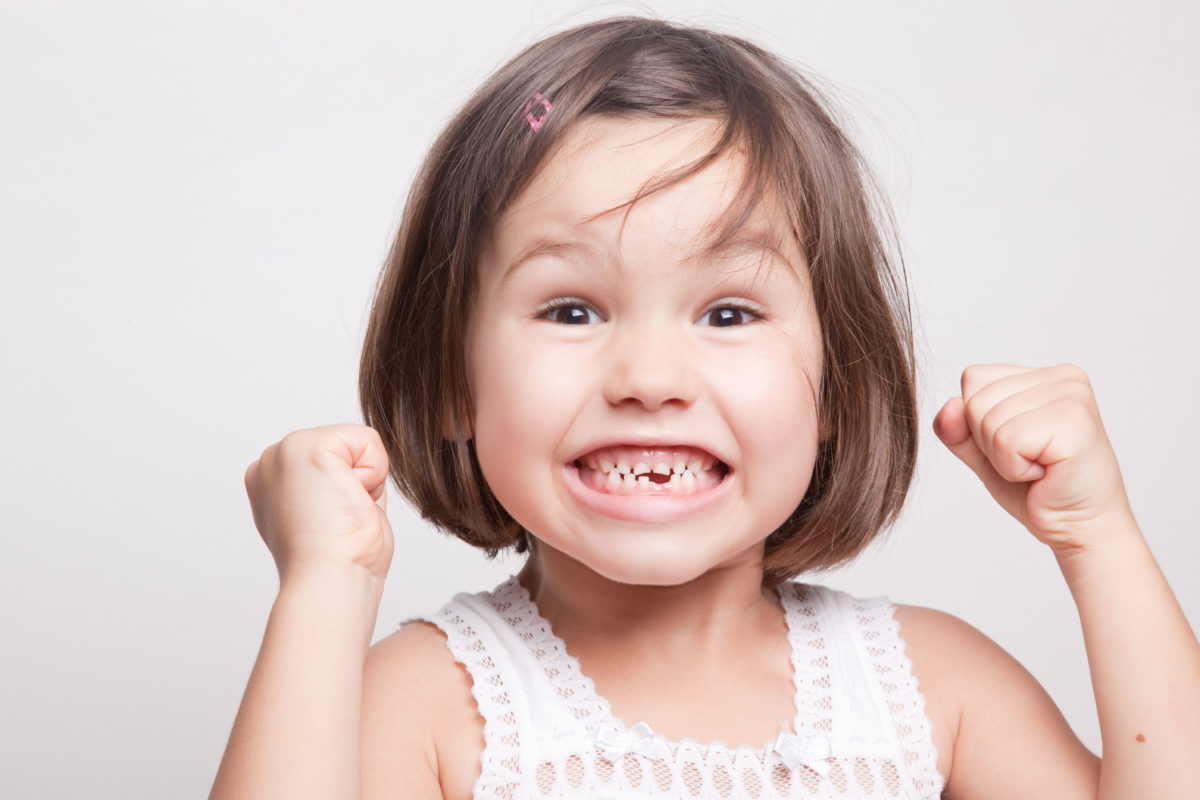 A little girl with her fists up in the air.