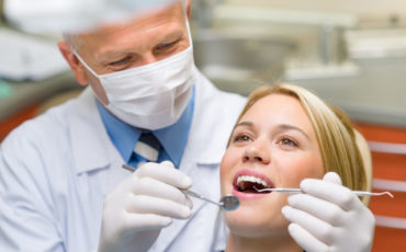 A dentist is examining a woman's teeth.