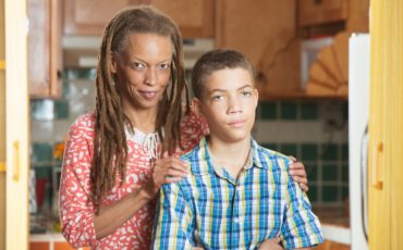 An african-american woman and her son standing in a kitchen.