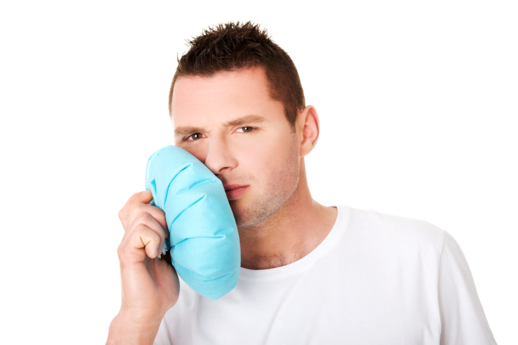 A man is holding a blue pillow over his mouth.