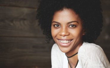 A young woman smiling with afro hair.