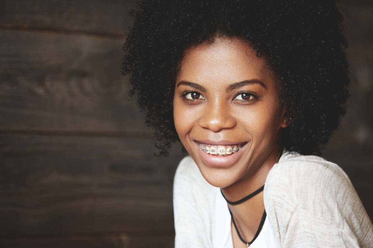 A young woman smiling with afro hair.