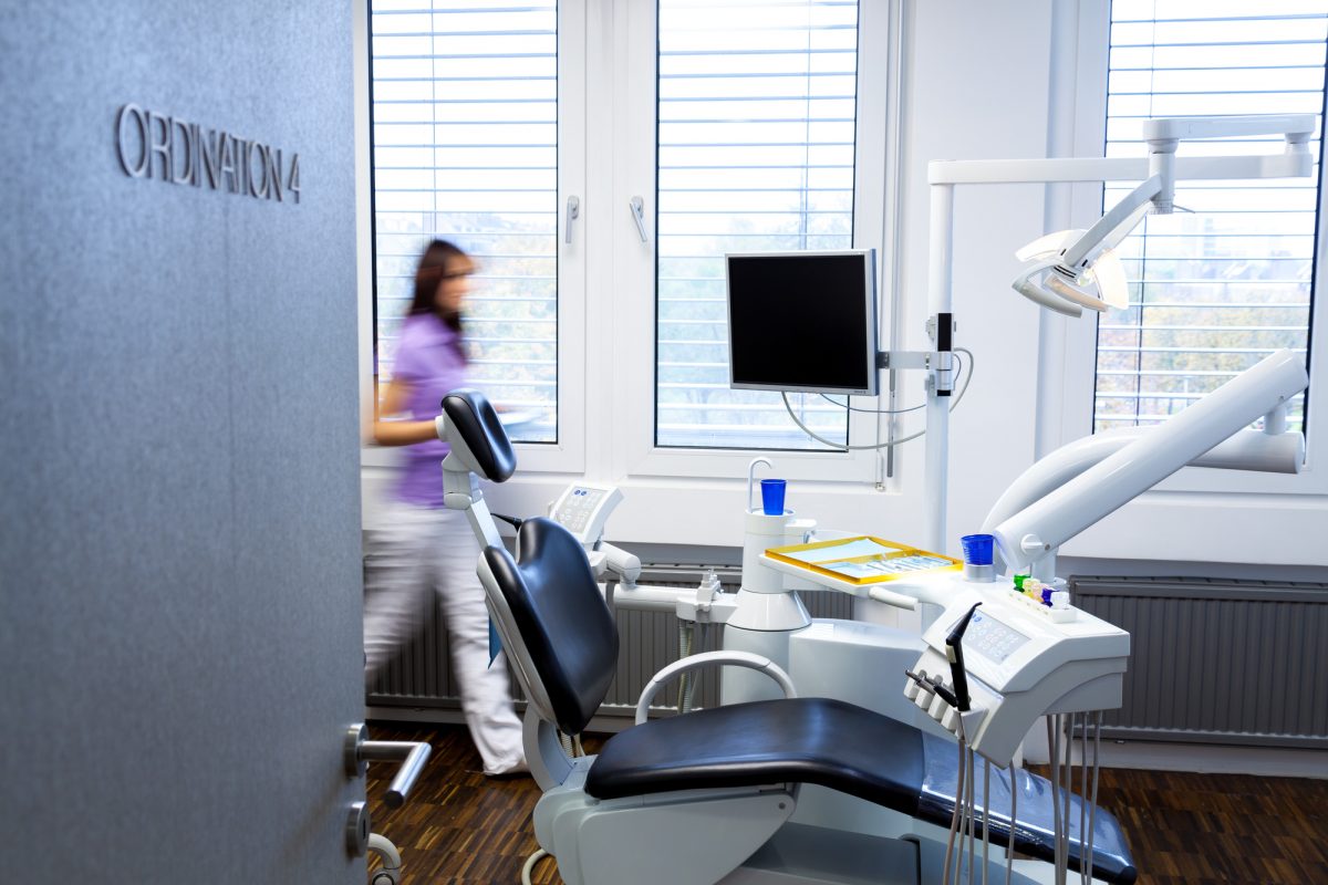 A woman walks past a dental chair in a dental office.