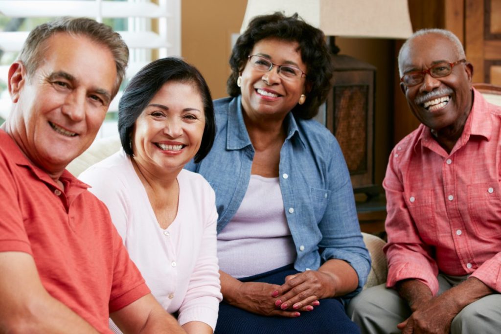 A group of older people sitting on a couch and smiling.