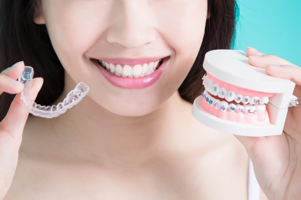 A woman holding a set of braces on a blue background.